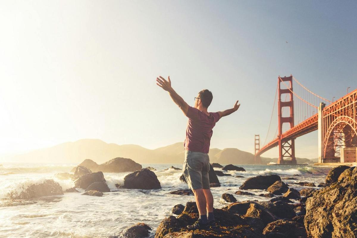 muž stojící na skalách před mostem Golden Gate