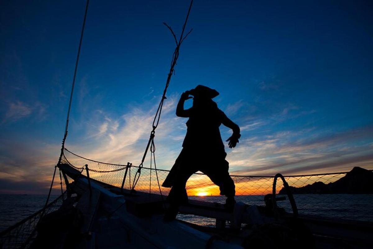 Un hombre está parado en un barco al atardecer.