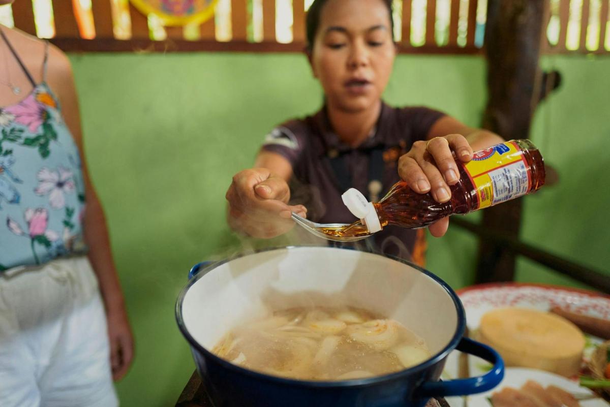una persona que vierte líquido en una olla de comida