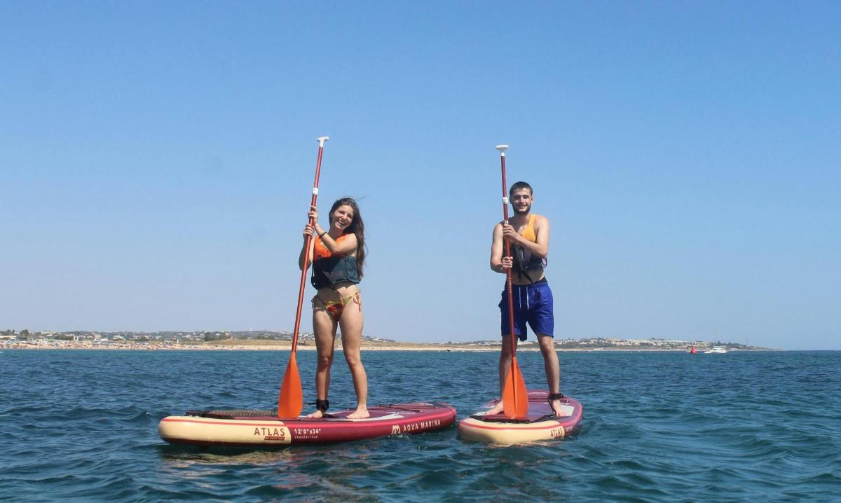 două persoane stau pe plăci de paddle în apă