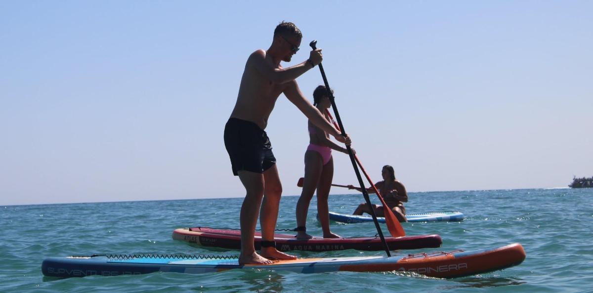 un grup de oameni care stau pe plăci de paddle în apă