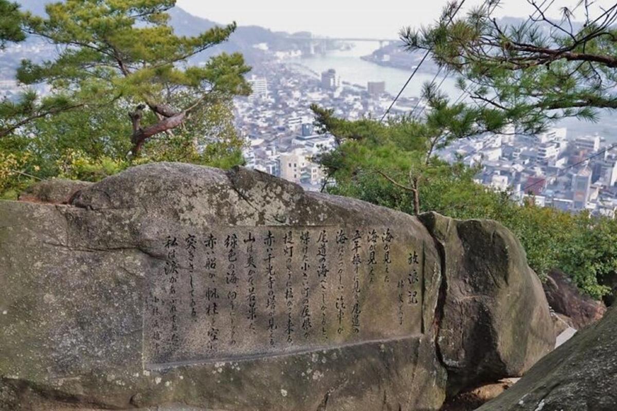 a stone monument on top of a hill with a city