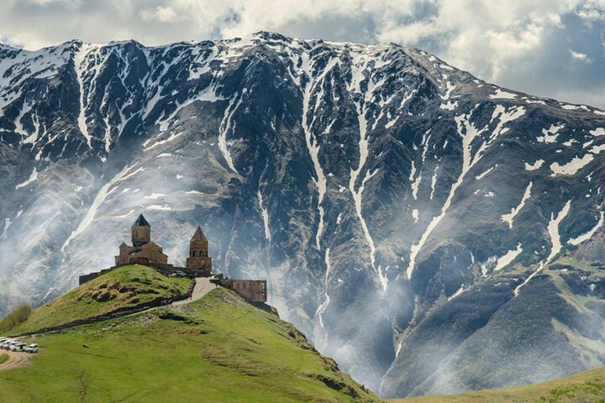 a castle on a hill in front of a mountain