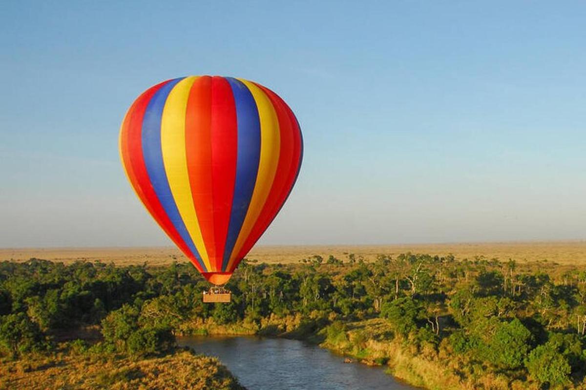 Barevný horkovzdušný balón letící nad řekou