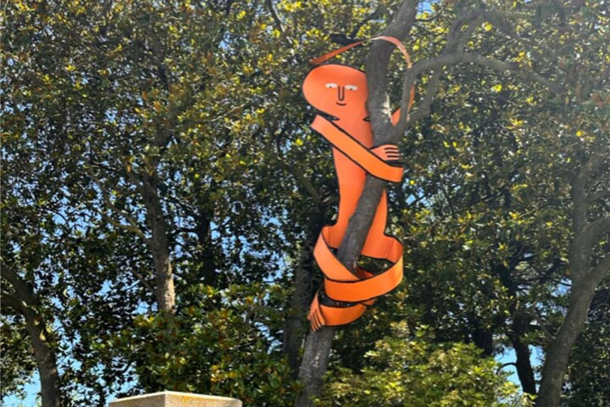 a sculpture of a person hanging from a tree