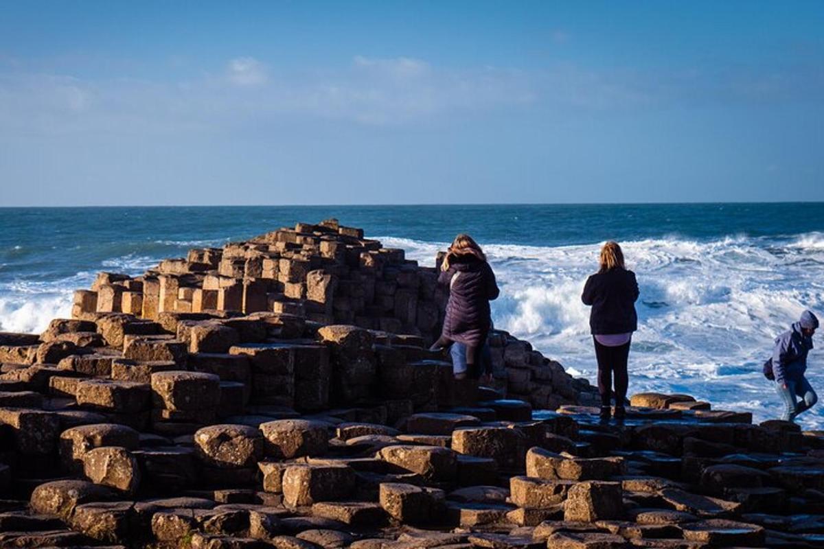 a group of people standing on a rock wall near the ocean