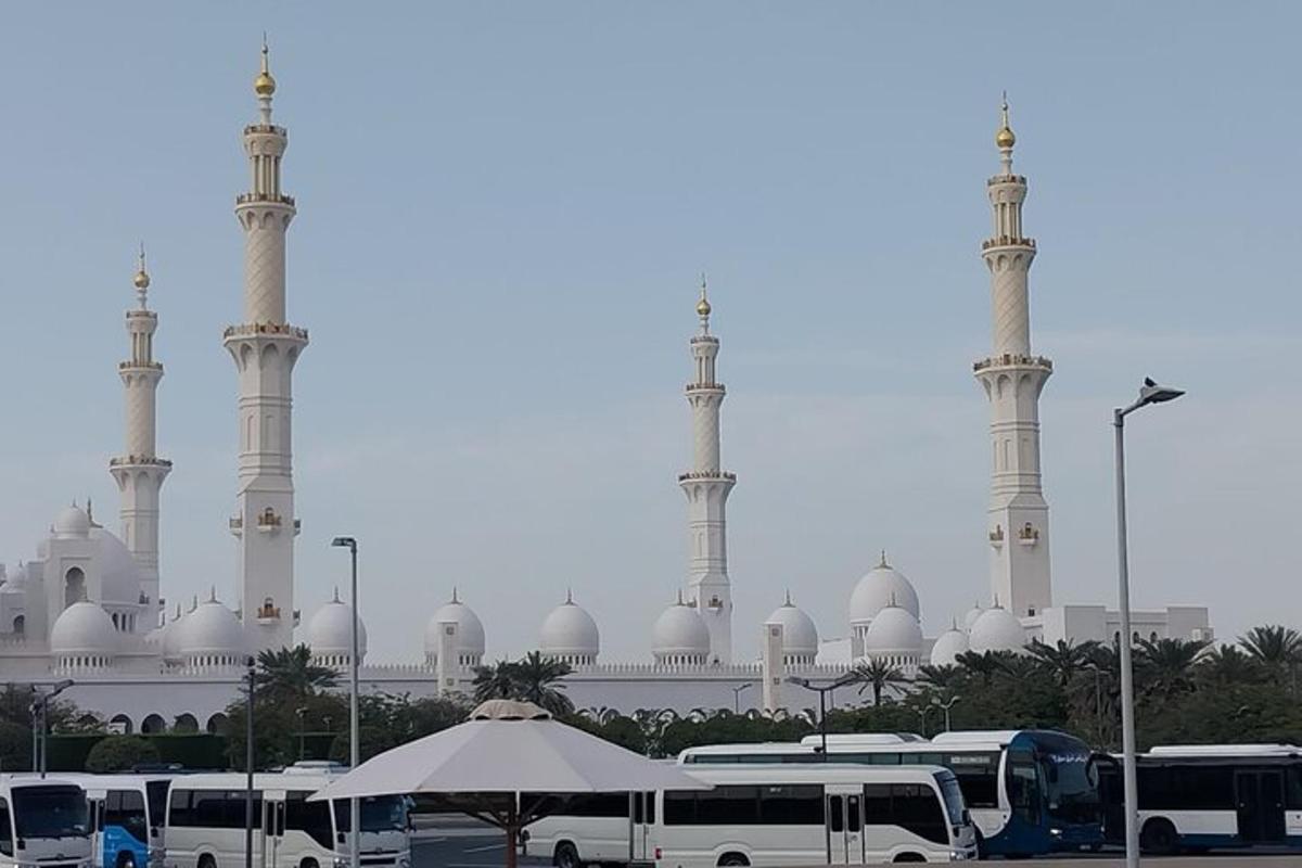 eine Moschee mit weißen Kuppeln und weißen Bussen davor