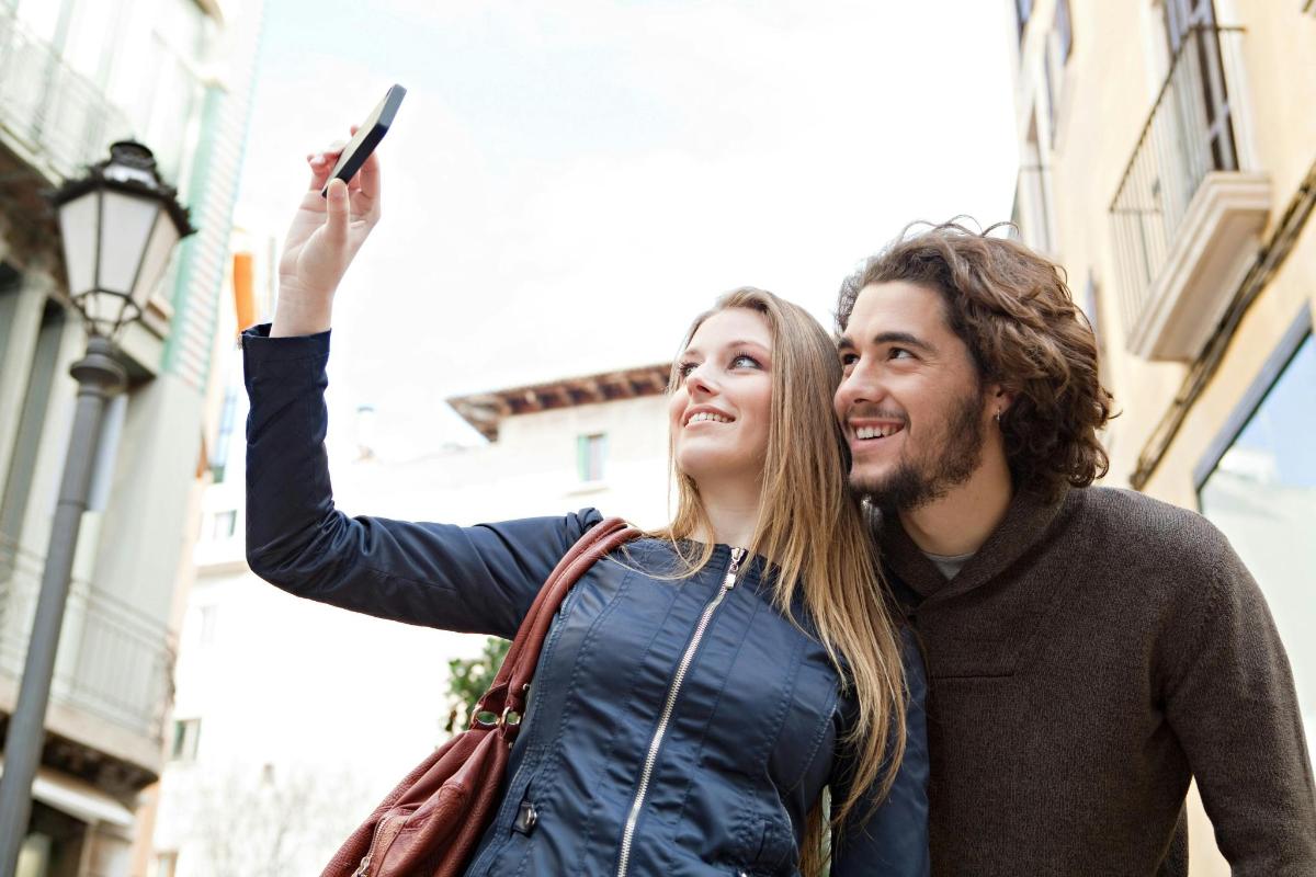 moški in ženska, ki se fotografirata z mobilnim telefonom