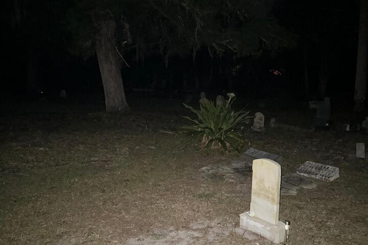 μια ταφόπλακα σε μια αυλή τη νύχτα με ένα δέντρο