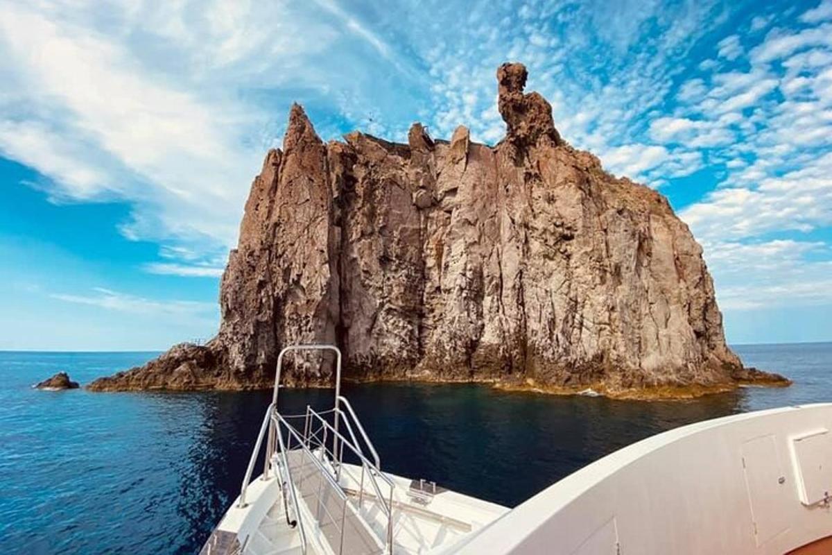 a boat in the water next to a rock formation