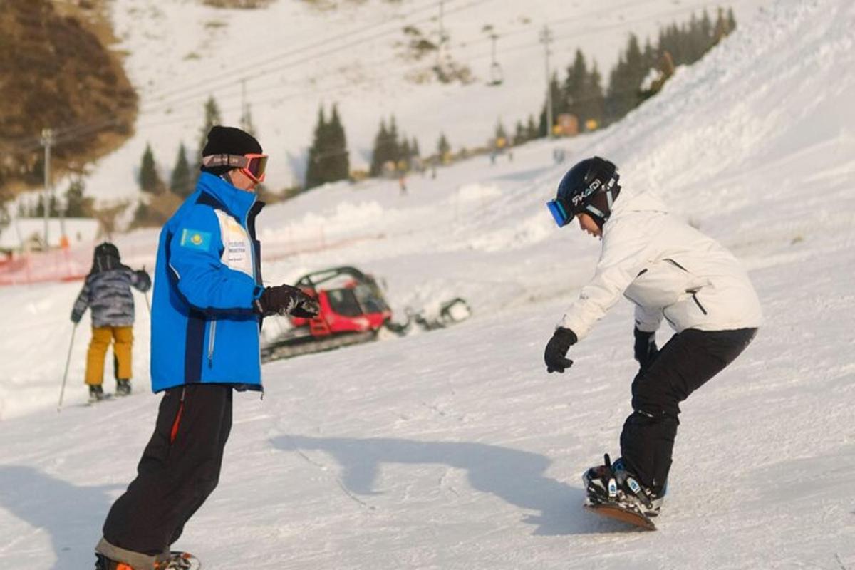 zwei Personen fahren mit dem Snowboard einen schneebedeckten Hang hinunter