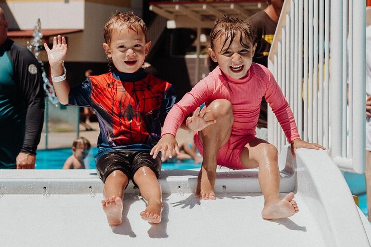 zwei kleine Kinder spielen auf einer Rutsche in einem Schwimmbad