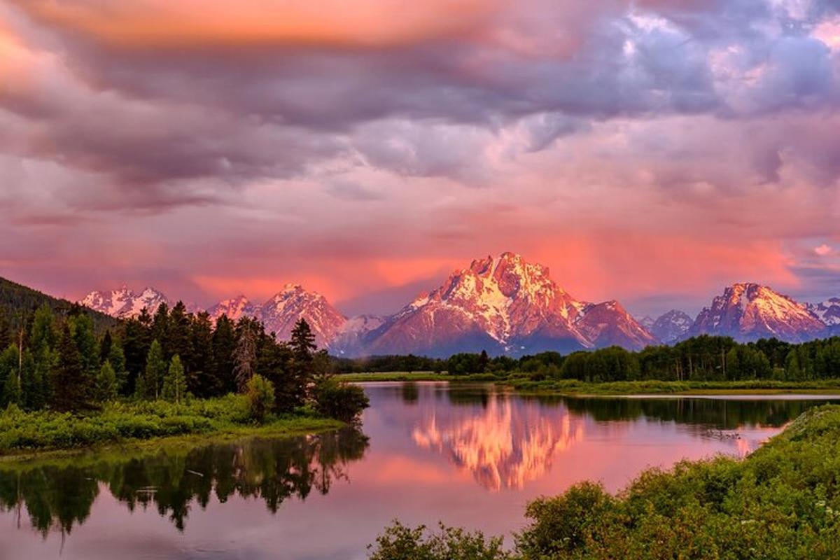 a sunset over a river with mountains in the background