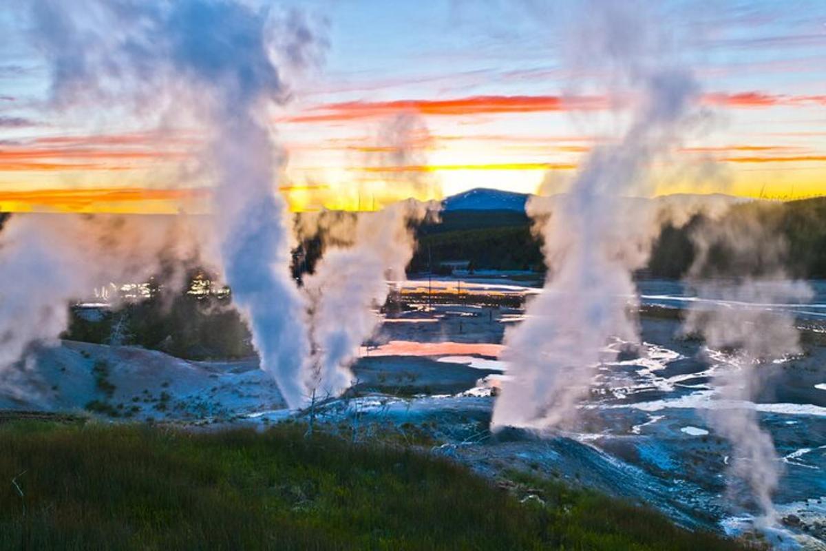 a group of geysers in the water at sunset