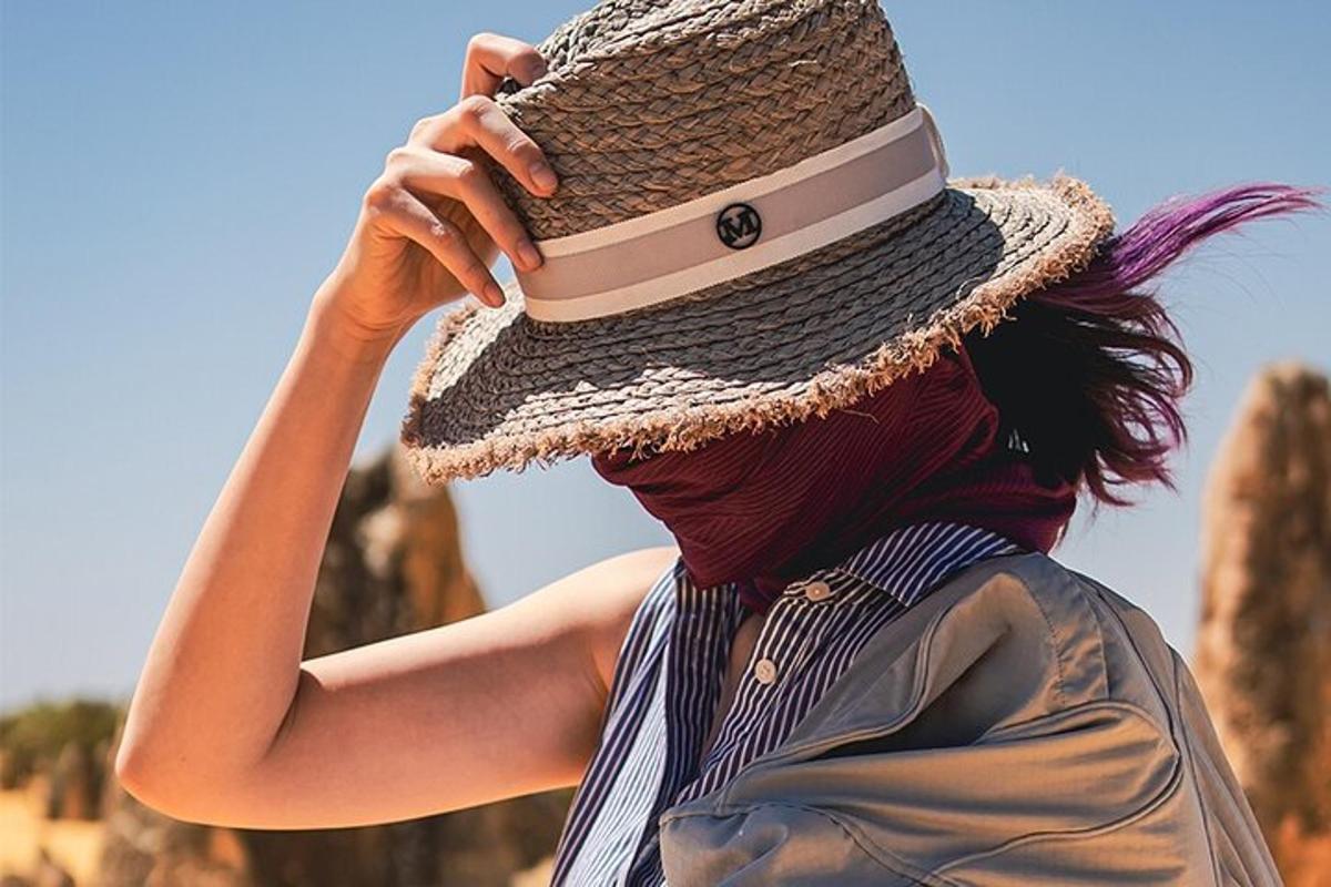 seorang wanita memakai topi jerami bercakap di telefon bimbit