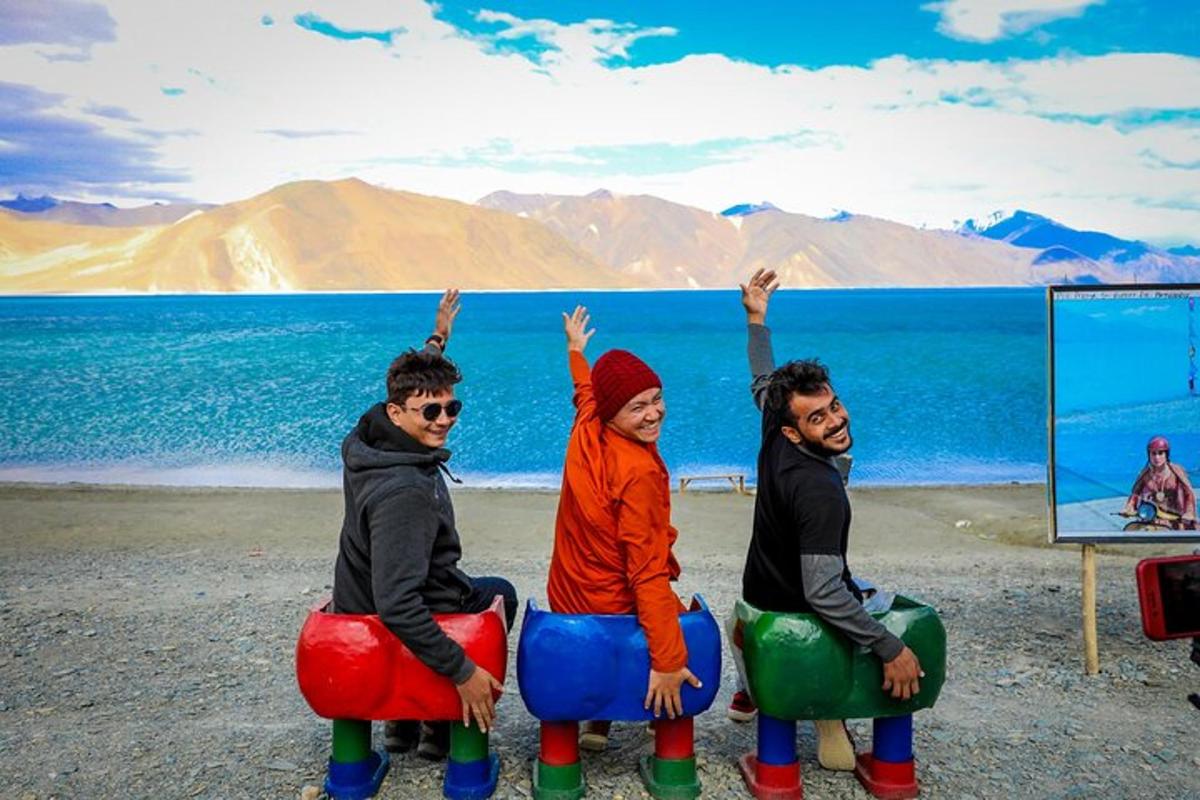 a group of three people sitting on bean bags by the water