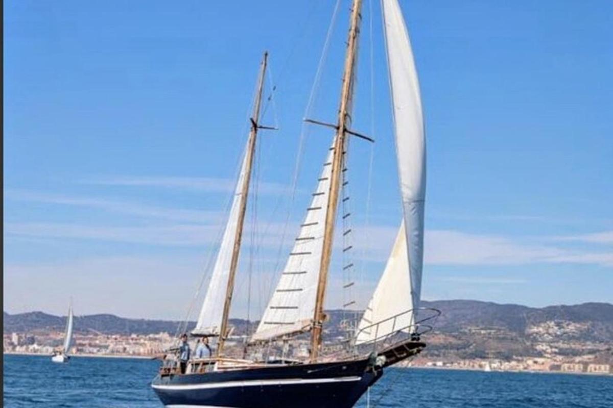 ένα ιστιοφόρο με άσπρα πανιά είναι στο νερό