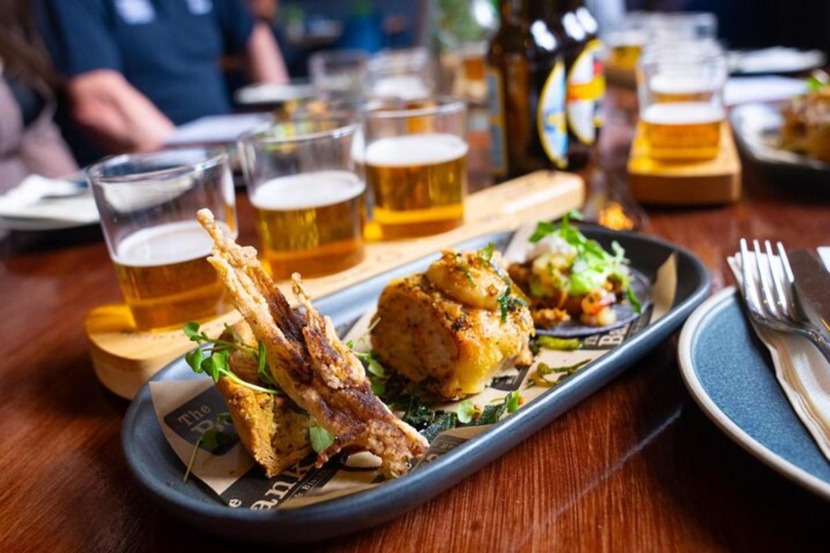 a plate of food on a wooden table with glasses of beer