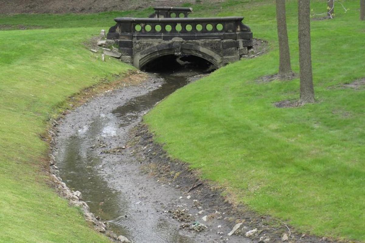 a small bridge over a stream in a field