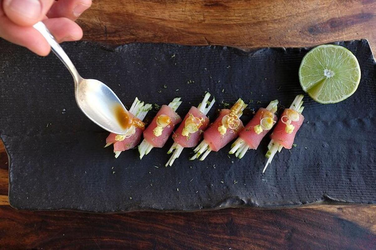 a person holding a spoon next to a bunch of sushi