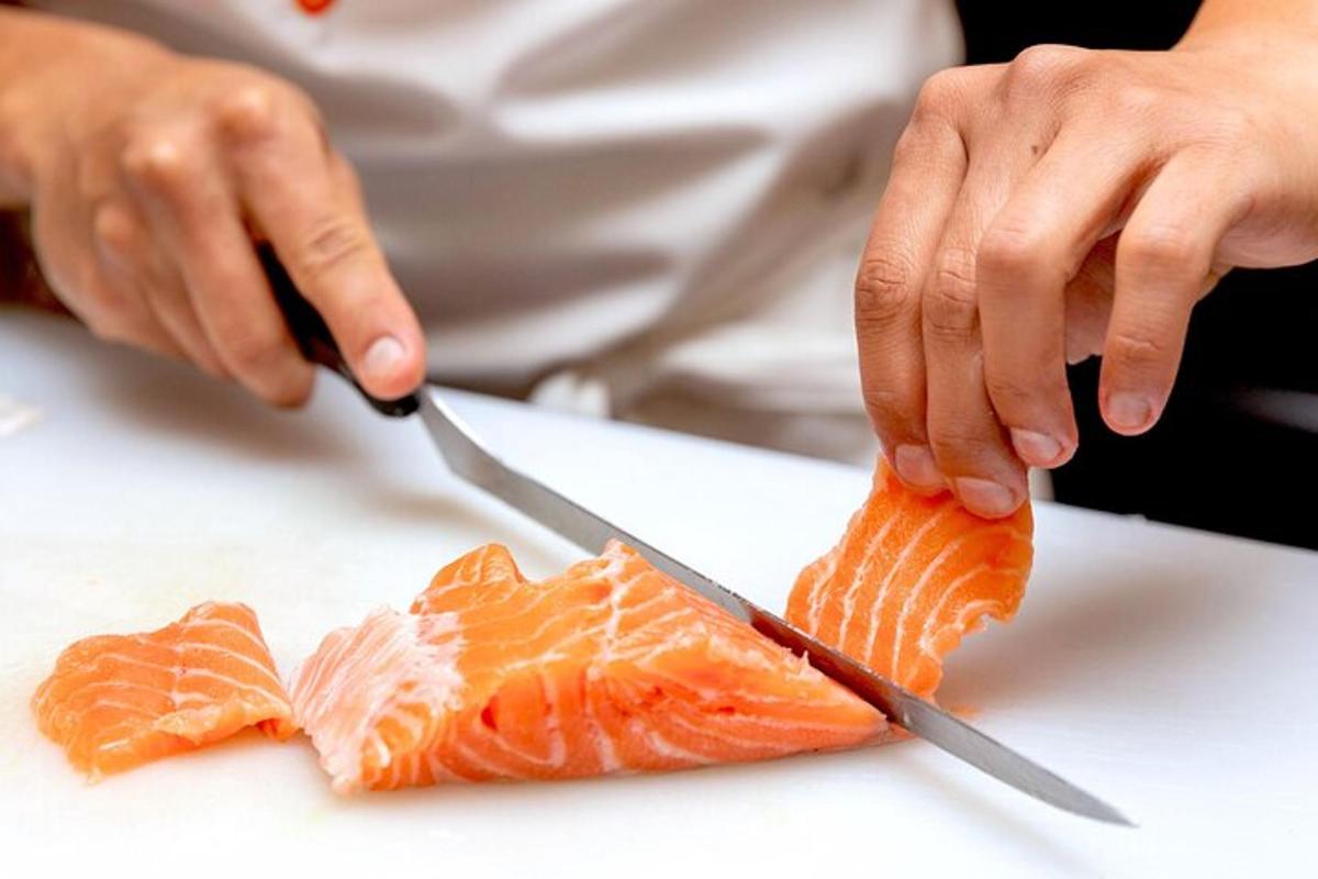 uma pessoa cortando um pedaço de sushi com uma faca