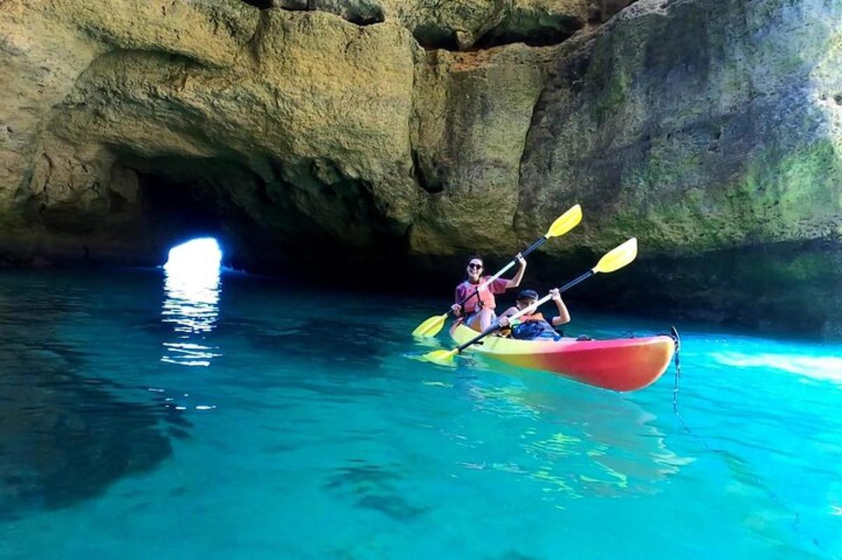 hai người trong một chiếc thuyền kayak trong nước gần một hang động