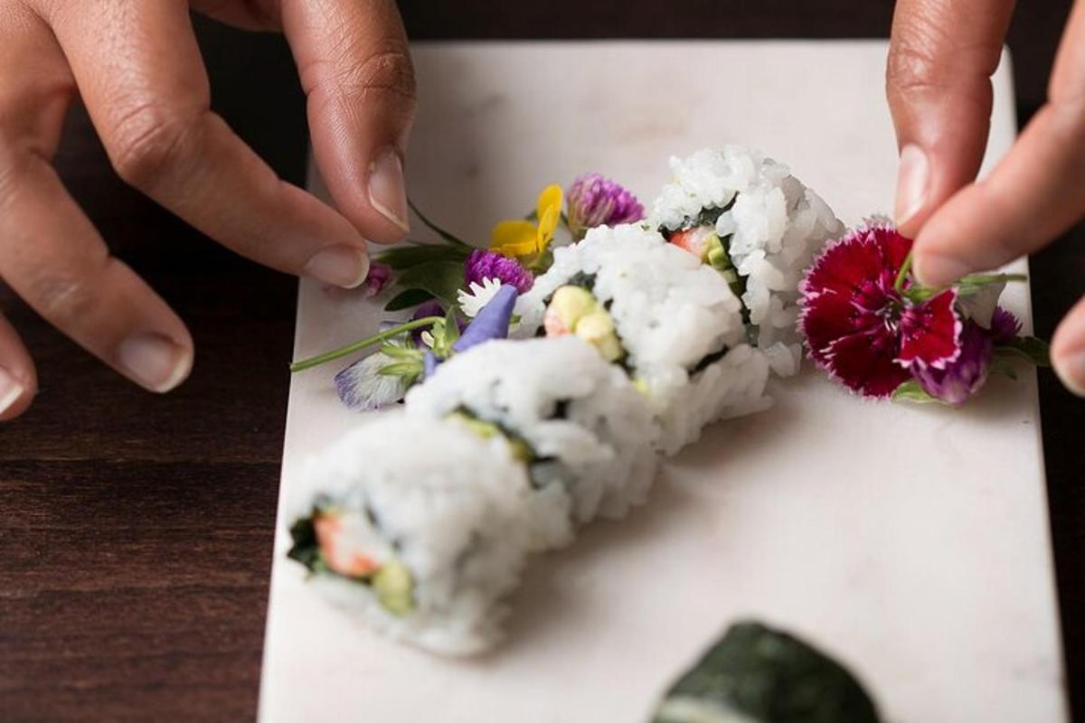 a person is holding a piece of sushi with flowers