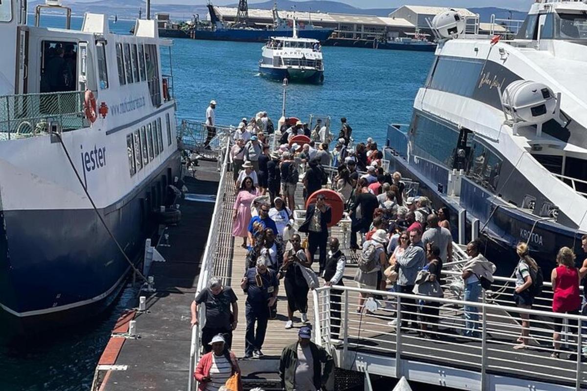 hópur fólks gengur á bryggju við hliðina á tveimur bátum