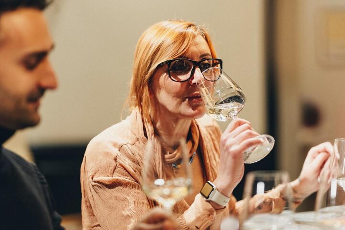 žena sedící u stolu se sklenicí vína