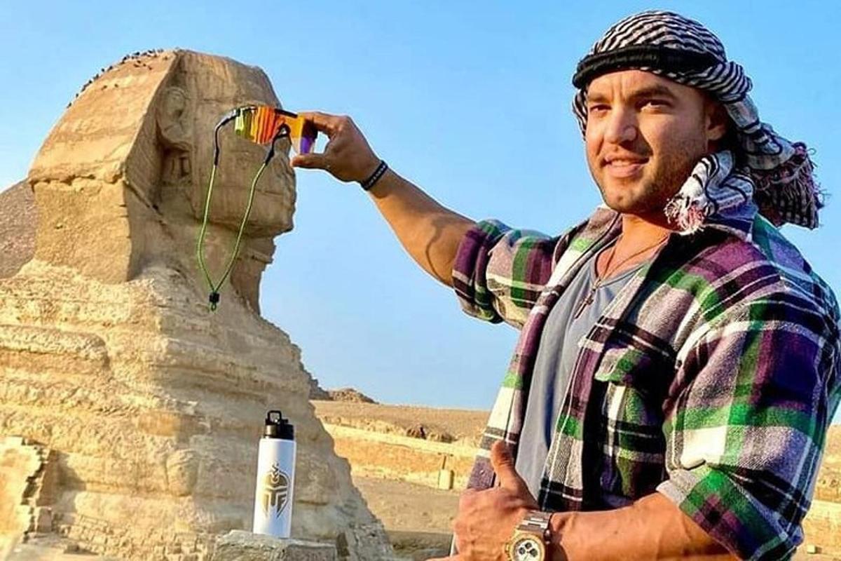 un bărbat care ține un zmeu în fața unei piramide