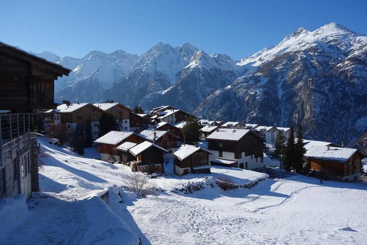 a village covered in snow with mountains in the background