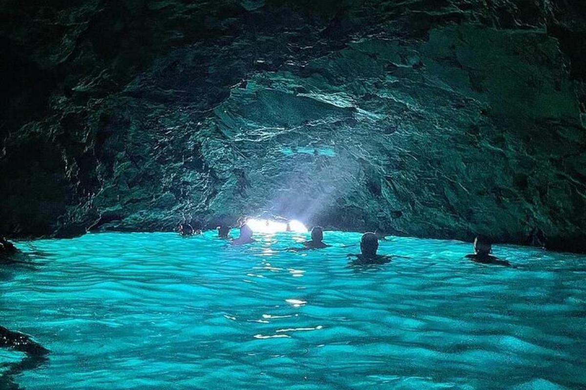 Skupina lidí plave v modré jeskyni