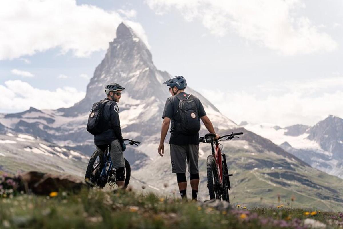 two men standing on a mountain with their bikes