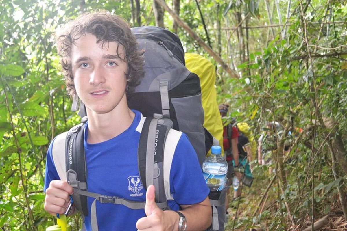a young man giving a thumbs up with a backpack