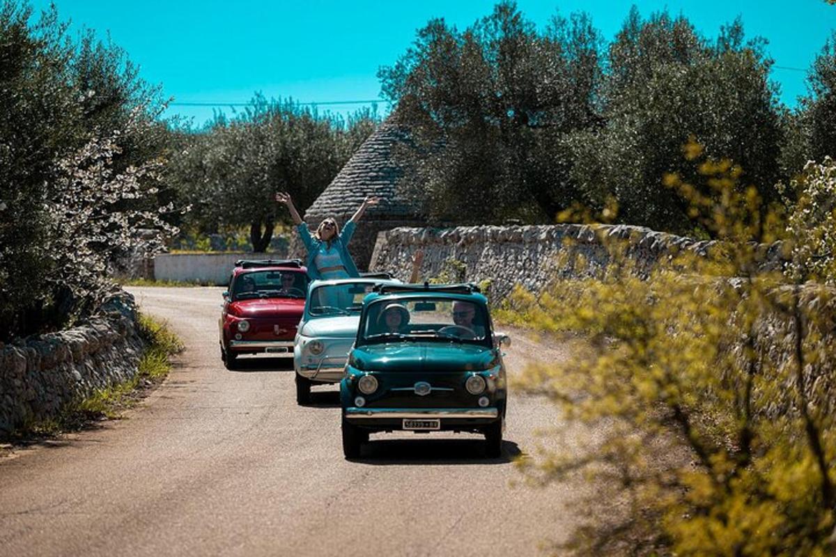 dois carros velhos estacionados em uma estrada com um homem em cima