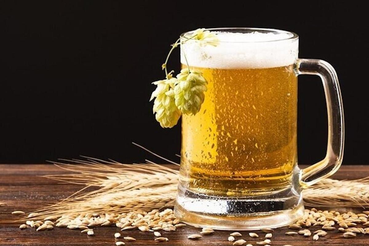 Un vaso de cerveza sobre una mesa con granos.