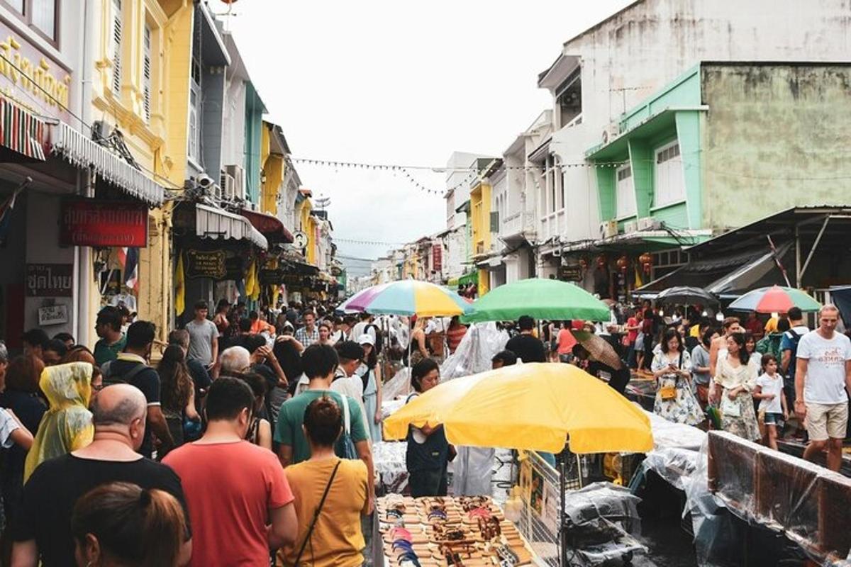 una folla di persone che camminano in un mercato con gli ombrelli