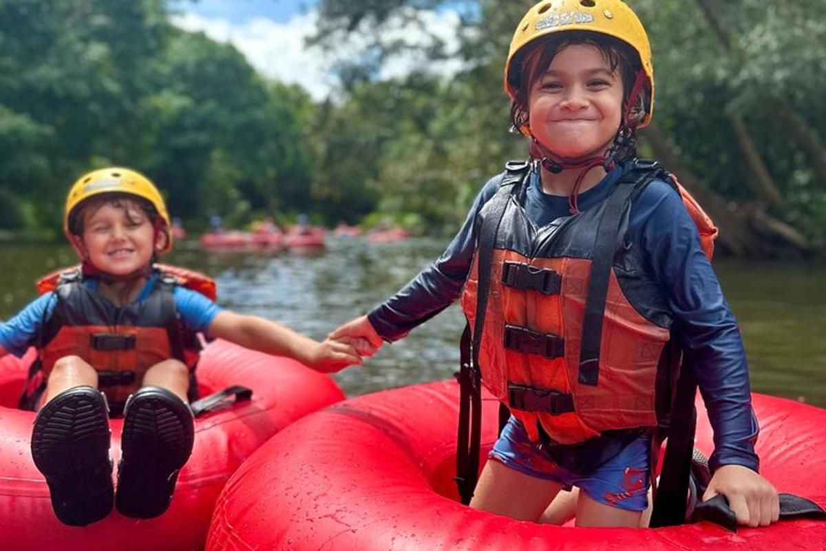 two young children wearing helmets on a raft on a river