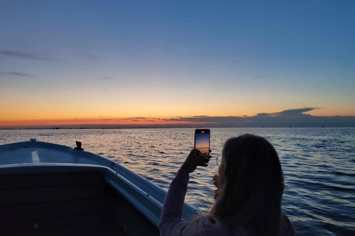 žena fotící západ slunce na lodi