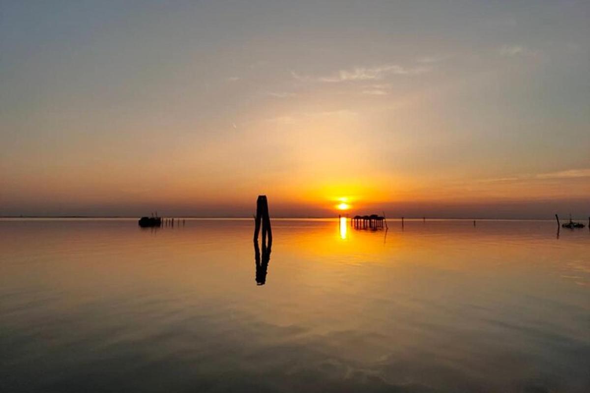 um poste na água com um pôr do sol ao fundo