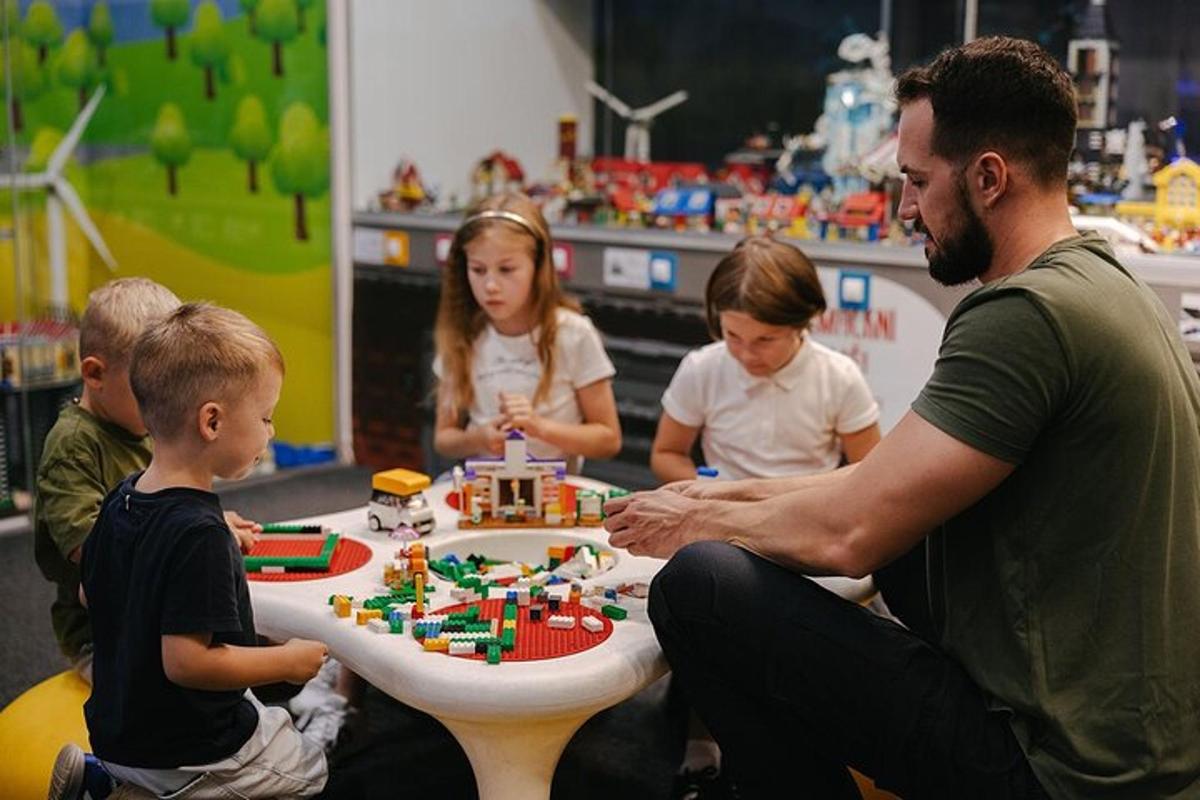 sekelompok anak-anak duduk mengelilingi meja dengan kue lego
