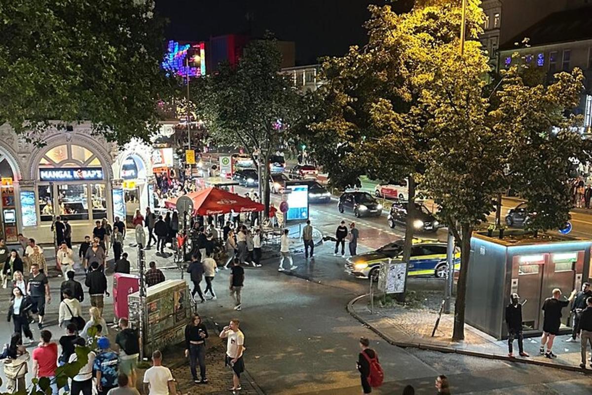 eine Menschenmenge, die nachts auf einer belebten Straße in der Stadt spazieren geht