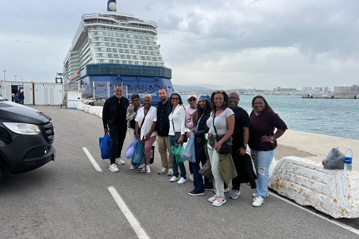 um grupo de pessoas em pé em frente a um navio de cruzeiro