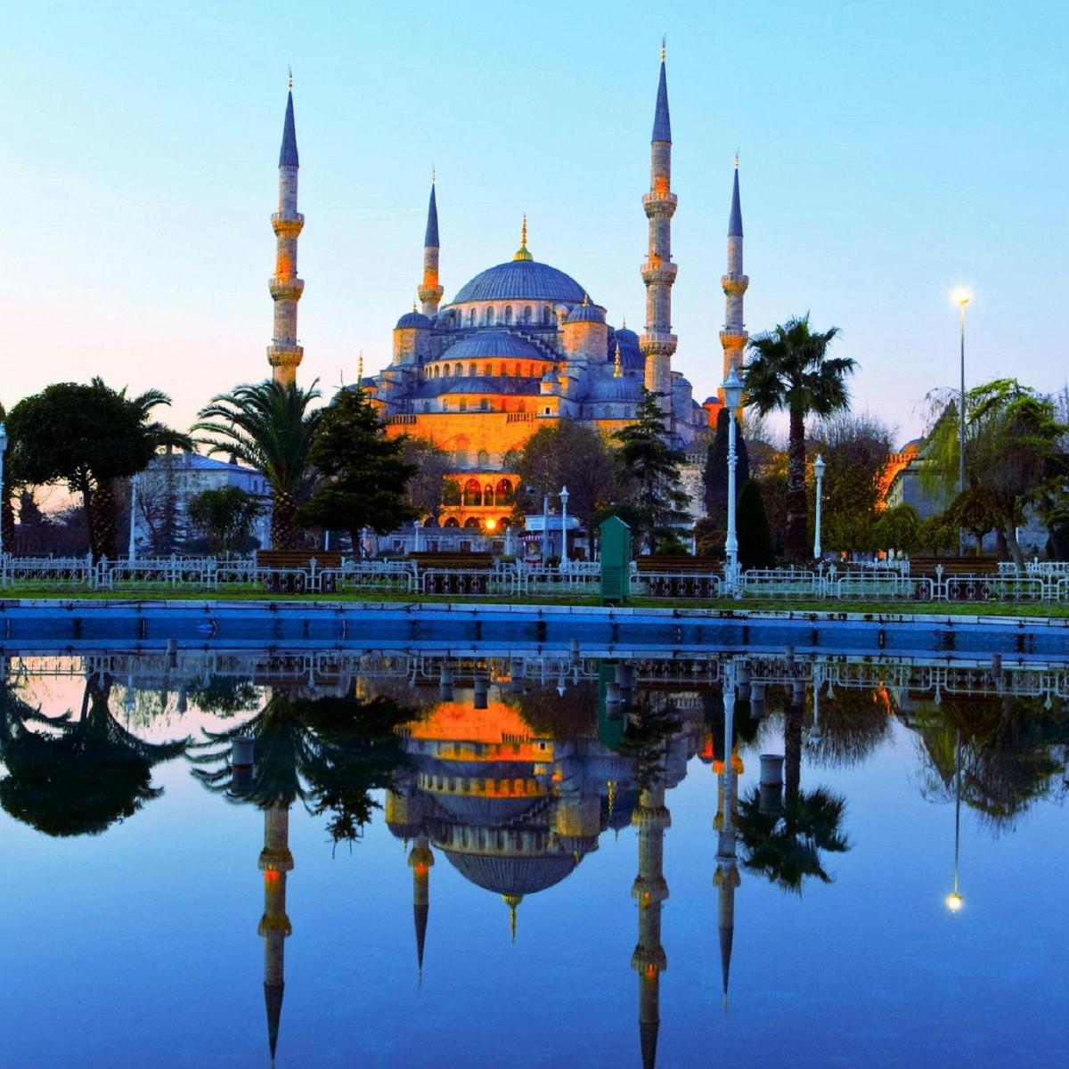 a mosque with its reflection in the water at dusk