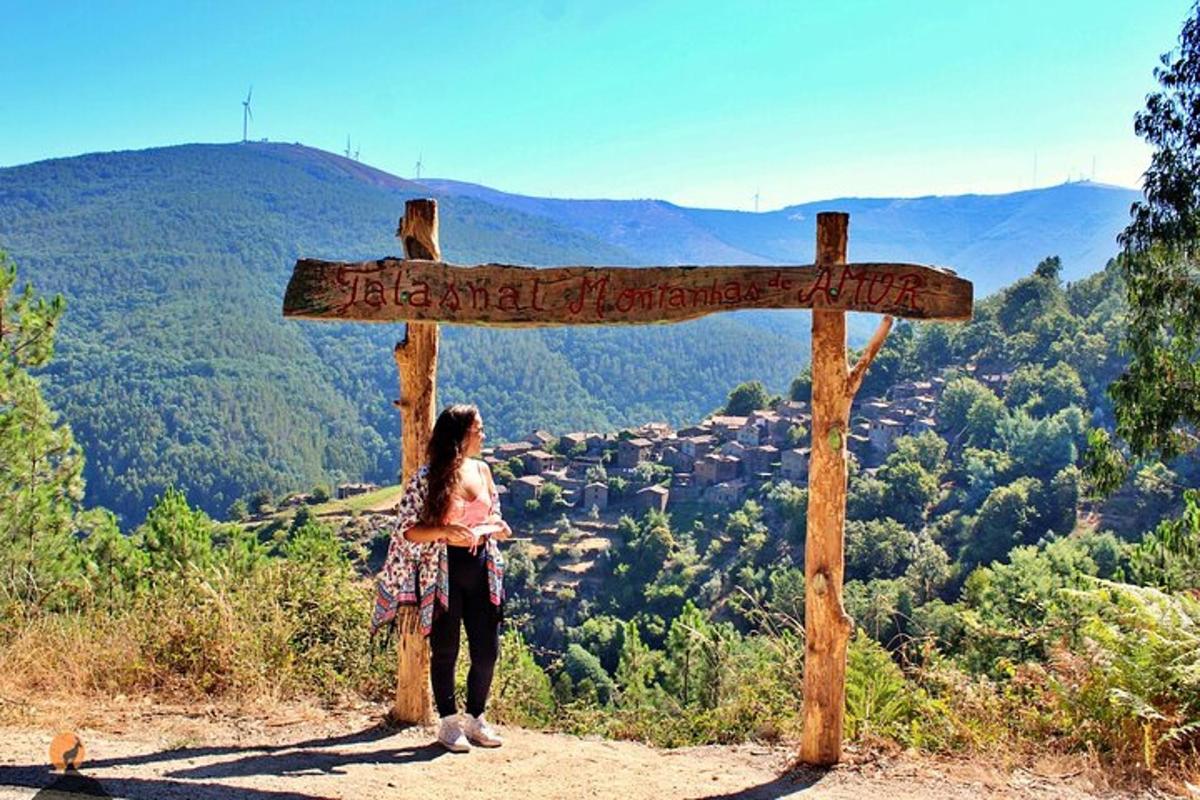 uma mulher parada ao lado de uma placa de madeira em uma montanha