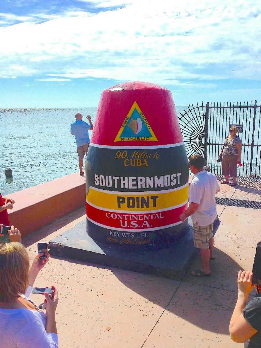 a group of people taking pictures of a sign on the beach