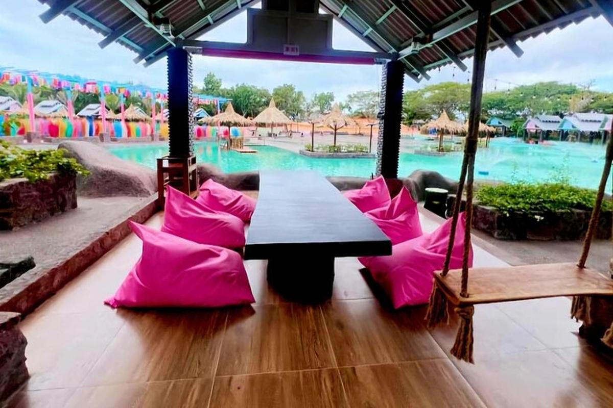 một chiếc bàn có gối màu hồng trước hồ bơi