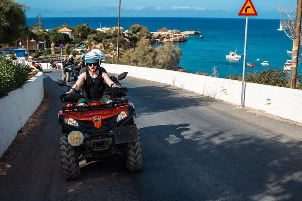 un home que condueix un quad per una carretera a prop de l'oceà