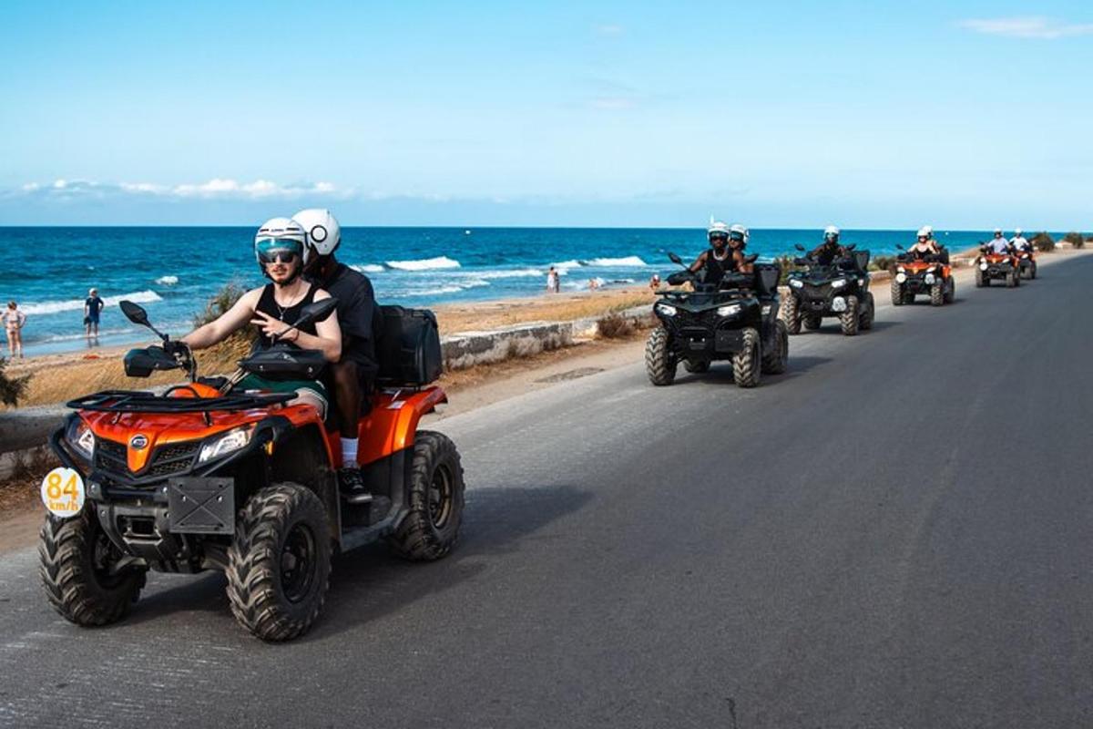 un grup de persones conduint quads per una carretera a prop de la platja