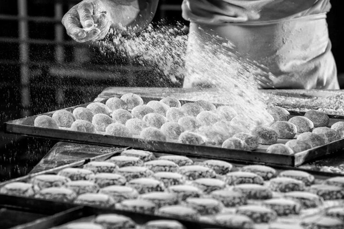 seseorang sedang menabur donat tepung di atas meja